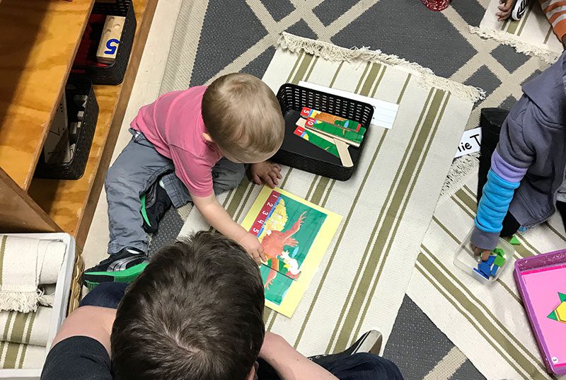 A young child reading a book at Sugar Mill Montessori School